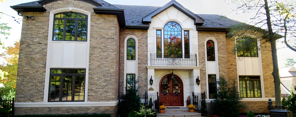 Tan brick house with arched windows and red double front door